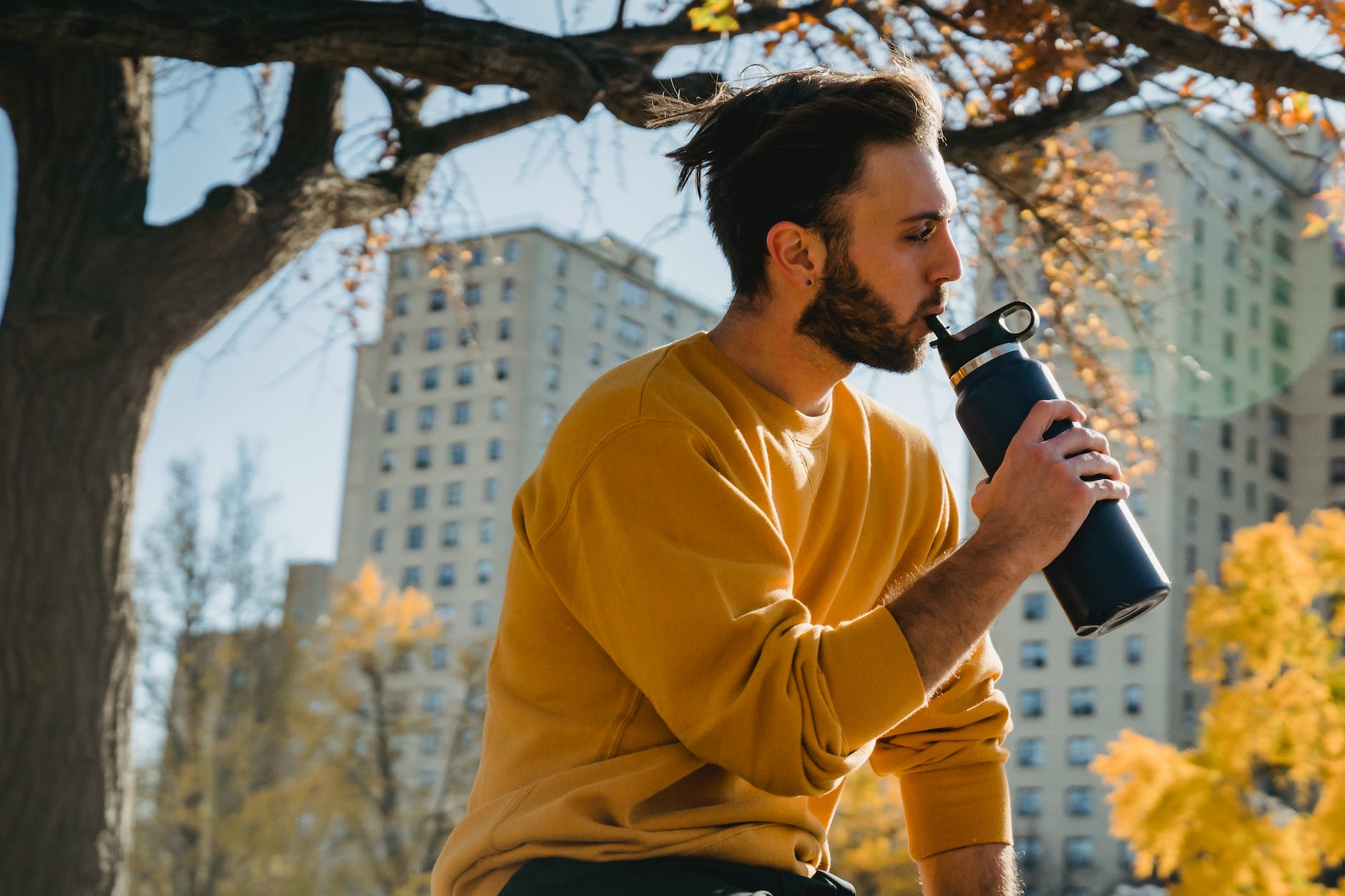 a man outside drinking from a reusable water bottle 