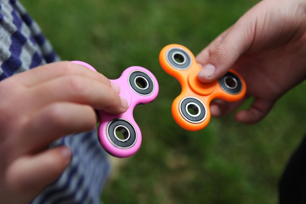 two kids playing with fidget spinners 